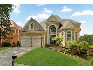 Beautiful brick home with a well-manicured lawn, two-car garage, and stunning architectural details at 5335 Davenport Mnr, Cumming, GA 30041