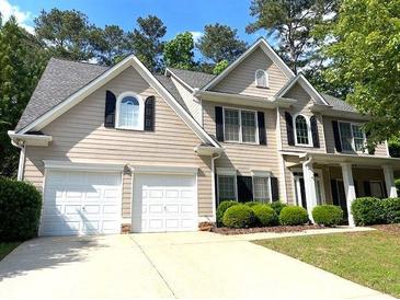 Charming home featuring a two-car garage, manicured shrubs, and a well-maintained front lawn at 6131 Windflower Dr, Powder Springs, GA 30127