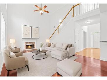 Bright living room featuring high ceilings, a cozy fireplace, and an elegant staircase leading to the upper level at 6131 Windflower Dr, Powder Springs, GA 30127