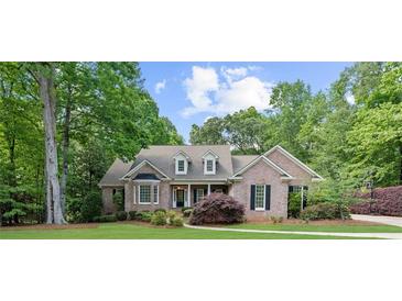 Charming brick home with lush landscaping, mature trees, and a well-manicured lawn at 3445 Strawberry Ln, Cumming, GA 30041