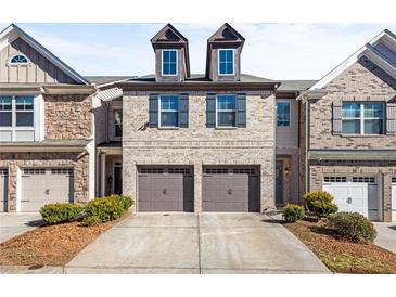 Charming brick townhouse featuring a two-car garage, dormers, and well-maintained landscaping at 2069 Brightleaf Way # 123, Marietta, GA 30060