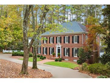 Charming brick two-story home with black shutters, mature landscaping, and a circular driveway surrounded by colorful trees at 769 Hampton Sw Pl, Marietta, GA 30064