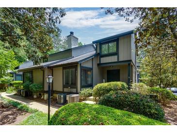 Two story home featuring a charming design and lush landscaping with mature trees and manicured bushes at 3102 Balearic Se Dr, Marietta, GA 30067