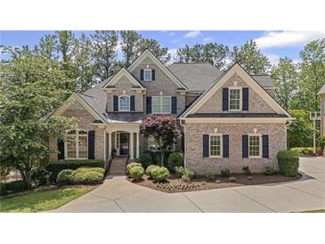 Stunning brick home featuring manicured landscaping, dark shutters, and a spacious driveway at 5293 Aldeburgh Dr, Suwanee, GA 30024