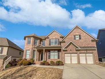 Beautiful two-story brick home with a two-car garage, manicured landscaping, and a welcoming front porch at 4449 Sierra Creek Dr, Hoschton, GA 30548