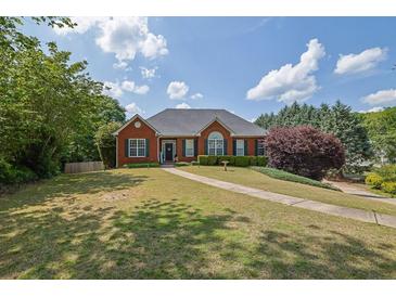 Charming one-story brick home boasts a well-manicured lawn and mature trees, offering great curb appeal at 6455 Crystal Ln, Cumming, GA 30040