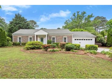 Charming brick ranch-style home with a well-manicured lawn, mature trees, and a two-car garage at 1000 Grimes Bridge Rd, Roswell, GA 30075