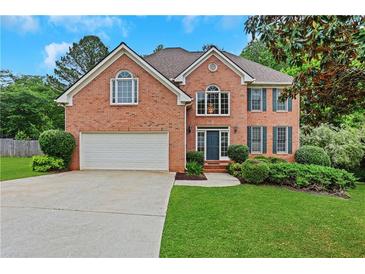 Charming brick home with well-manicured lawn, two-car garage, and inviting front entrance at 5435 Vicarage Walk, Alpharetta, GA 30005