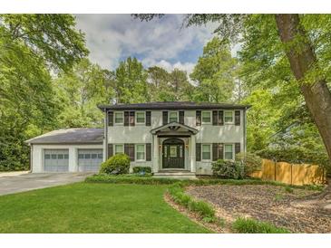 Beautiful two-story house with a well-manicured lawn and a two-car garage, surrounded by mature trees at 1615 Arden Sw Dr, Marietta, GA 30008