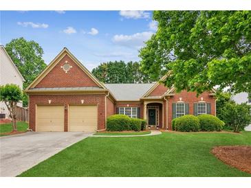 Charming brick home featuring a manicured front lawn and a two-car garage at 1815 Montcliff Dr, Cumming, GA 30041