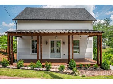 Charming two-story home with a covered front porch, manicured lawn, and brick-lined flower beds at 50 Maple St, Roswell, GA 30075