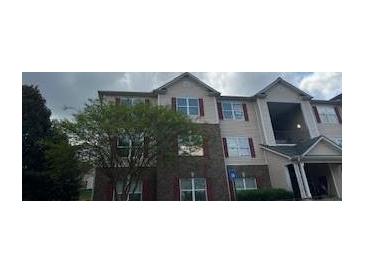 Exterior view of a three story building with brick and beige siding and multiple windows at 14301 Waldrop Cv, Decatur, GA 30034