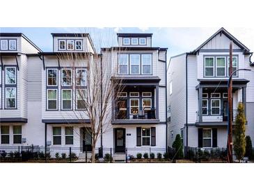 Modern townhome with white brick and gray siding, complemented by black window trim and wrought iron fence at 915 Katie Kerr Drive, Decatur, GA 30030