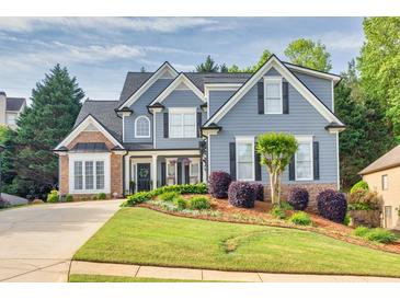 Charming two-story home featuring a manicured lawn, brick accents, and a welcoming front porch with black shutters at 3125 Flatbottom Dr, Dacula, GA 30019