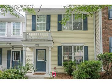 Charming townhome featuring light yellow siding, dark blue shutters, and a small balcony over the entry door at 3746 Berkeley Xing, Duluth, GA 30096