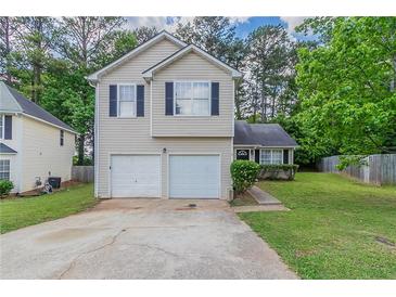 Two-story home featuring a two-car garage, neutral siding, and well-maintained landscaping at 2319 Rambling Way, Lithonia, GA 30058