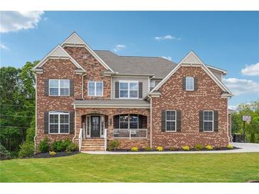 Charming two-story brick home featuring a covered porch and meticulously manicured lawn at 6375 Haystack Ct, Cumming, GA 30040