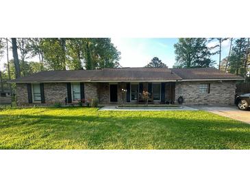 Traditional brick home with a well-manicured lawn and mature trees at 661 Oak Dr, Riverdale, GA 30274