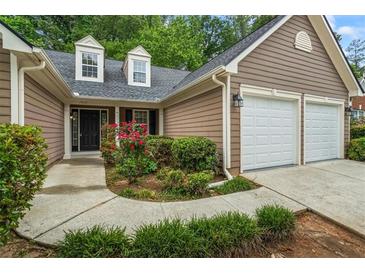 Charming home with two-car garage, manicured front yard, and welcoming entryway with black door at 1909 Riverlanding Cir, Lawrenceville, GA 30046