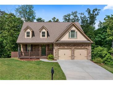 Charming two-story home featuring a brick facade, inviting front porch, well-manicured lawn, and attached two-car garage at 42 Treemont Se Dr, Cartersville, GA 30121