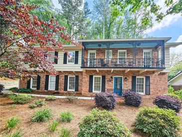 Two-story brick home featuring a balcony, landscaped front yard, black shutters, and a blue front door at 2151 Desmond Dr, Decatur, GA 30033