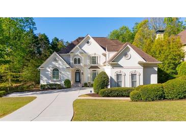 Beautiful white two-story home with manicured landscaping and a concrete driveway at 5685 Commons Ln, Alpharetta, GA 30005