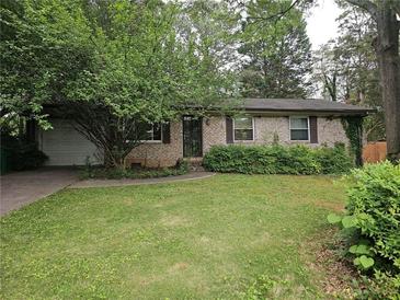 Charming single-story brick home with a well-manicured lawn and mature trees shading the front at 1517 Colony East Cir, Stone Mountain, GA 30083