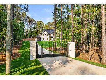 View of gated entrance and long drive to a stately, modern farmhouse nestled in a wooded lot at 400 Auburn Rd, Auburn, GA 30011