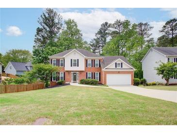 Charming two-story brick home with a well-maintained lawn and attached two-car garage at 1812 Riverton Dr, Suwanee, GA 30024