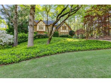 Charming home with lush greenery, trees, and lawn creating curb appeal and an inviting landscape at 375 Spindle Ct, Sandy Springs, GA 30350
