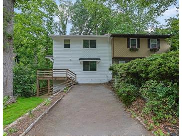 View of the home's exterior with a two-car driveway and stairs to front deck nestled in a wooded landscape at 2551 Park Se Rd, Smyrna, GA 30080
