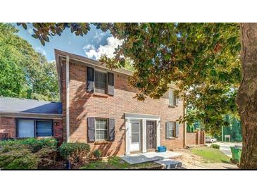 Inviting brick-facade home with black shutters, front lawn, and beautiful mature trees in a well-maintained neighborhood at 115 Plantation Dr, Clarkston, GA 30021