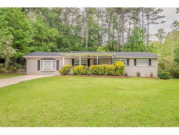 Charming ranch-style home featuring a spacious front yard, mature trees, and a covered entryway at 2212 Chestnut Log Loop, Lithia Springs, GA 30122