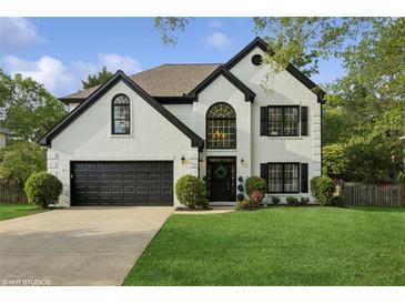 Charming two-story brick home with manicured lawn and a black two-car garage against a cloudy sky at 230 Bluff Oak Dr, Roswell, GA 30076