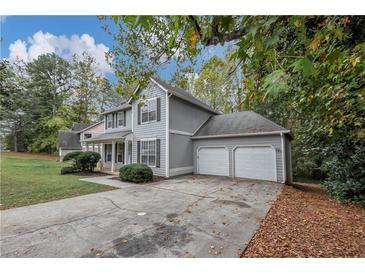 Two-story home featuring a two-car garage, gray siding, and a well-maintained front lawn at 565 Lake Joyce Ln, Fairburn, GA 30213