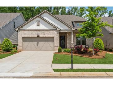Charming single-story home featuring a brick facade, well-manicured lawn, and an attached two-car garage at 3210 Steinbeck St, Cumming, GA 30041