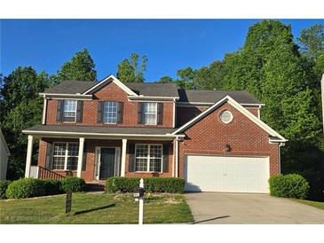 Charming two-story brick home featuring a covered front porch and a two car garage in a suburban neighborhood at 7491 Hilltop Way, Atlanta, GA 30349