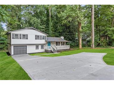 Inviting home with a two-car garage, a wide driveway, and a charming porch amidst lush greenery at 353 Old Rosser Rd, Stone Mountain, GA 30087