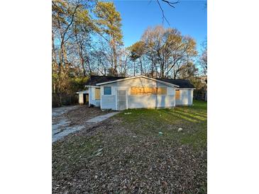 Modest single-story home with boarded windows and overgrown front lawn surrounded by mature trees at 274 Fairburn Nw Rd, Atlanta, GA 30331