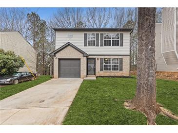 Charming two-story home features a brick accent, attached garage, and freshly landscaped front yard at 7074 Ravenwood Ln, Lithonia, GA 30038