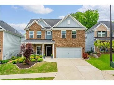 Two-story brick home with an attached two-car garage, manicured lawn, and a charming covered porch at 123 Woodford Ln, Canton, GA 30115