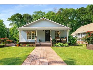 Charming single-story home featuring a quaint front porch, lush lawn, and inviting curb appeal with well-maintained landscaping at 1928 Main Nw St, Atlanta, GA 30318
