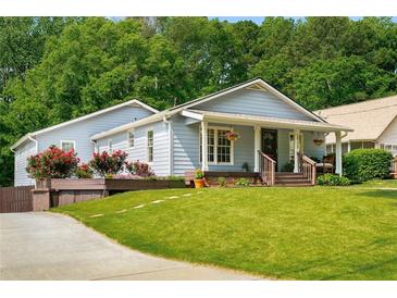Charming, light blue home featuring a covered front porch with lush landscaping and a well-manicured lawn at 1928 Main Nw St, Atlanta, GA 30318