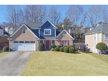 Charming two-story brick home with a well-manicured lawn, red shutters, and attached two-car garage at 690 Winding River Dr, Lawrenceville, GA 30046