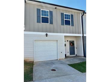 Charming townhome featuring a one-car garage and gray siding with complementary blue shutters at 4940 Elm Brook Dr, Atlanta, GA 30349