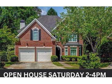 Charming brick home featuring a two-car garage, arched window, and well-maintained landscaping at 1187 Druid Walk, Decatur, GA 30033