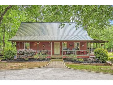 Charming cottage-style home with a metal roof, inviting front porch and attractive landscaping at 5419 Tyree Rd, Winston, GA 30187
