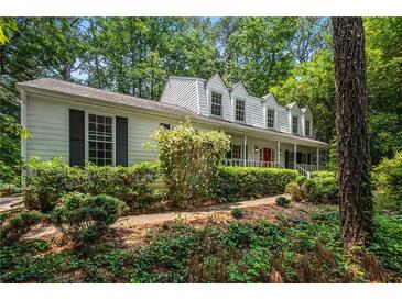 Charming home with a covered porch, beautiful landscaping, and mature trees offering curb appeal at 1229 Colony Cir, Marietta, GA 30068