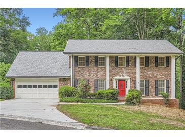 Traditional brick home with a red front door, white columns, and a well-manicured lawn at 2034 Starfire Ne Dr, Atlanta, GA 30345
