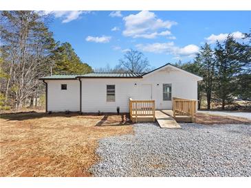 Charming single-story home with white siding, green metal roof, and a ramp for easy access at 4064 Post Rd, Winston, GA 30187